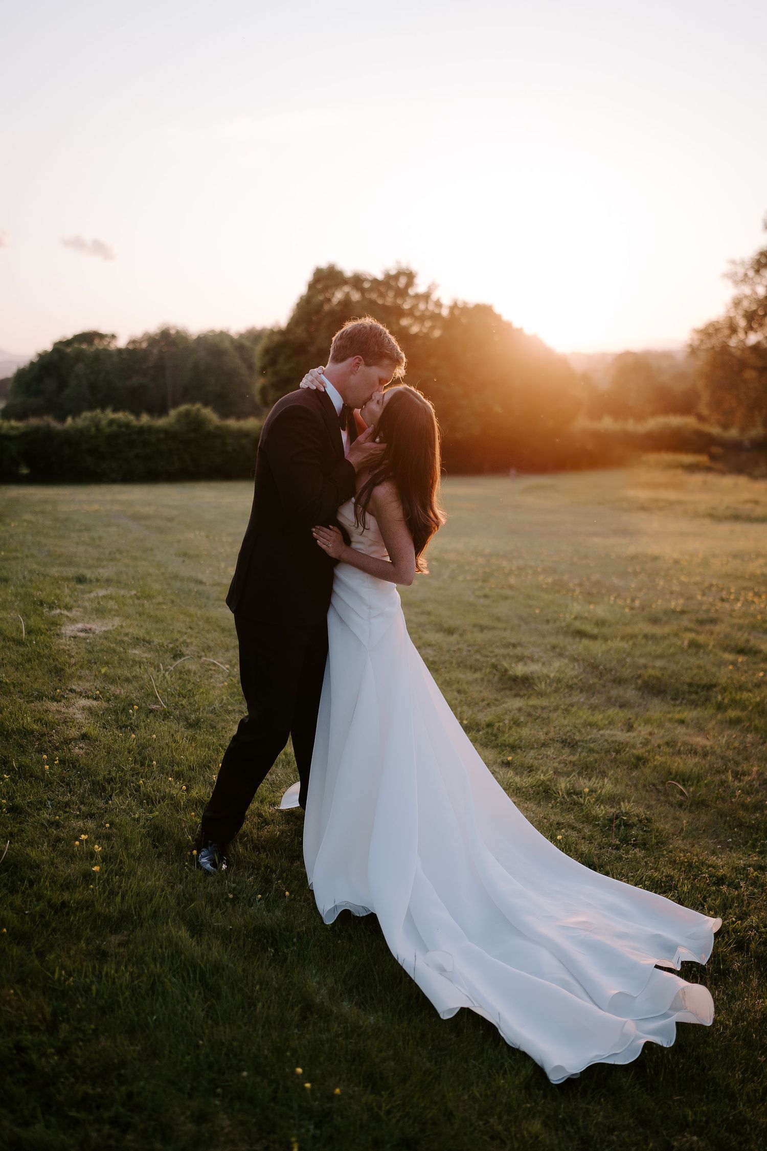 groom pulling bride in for a kiss in the setting sun at dewsall court in herefordshire