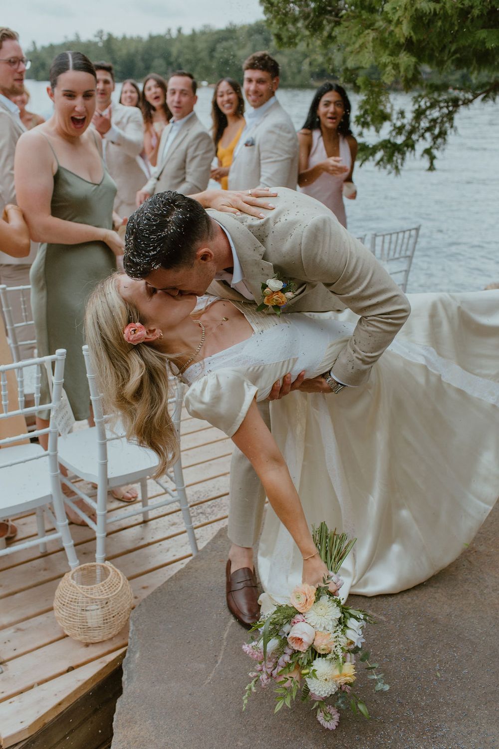 Energetic first kiss walking down the aisle on a dock in Muskoka. Howdy Pictures - film wedding & elopement photographers in Canada & NZ