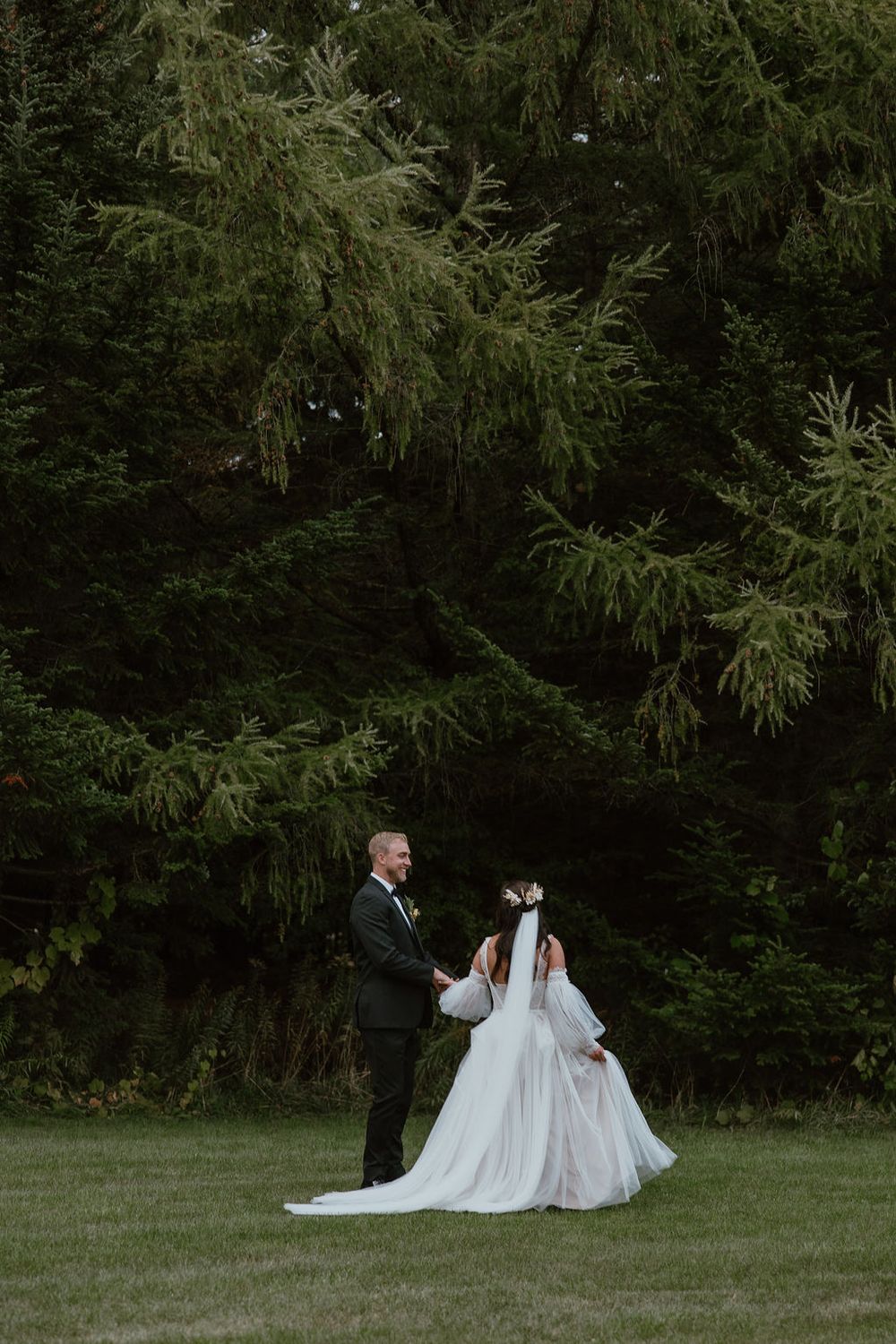 Blurry romantic couple running toward evergreens. Howdy Pictures - film wedding & elopement photographers in Canada & New Zealand