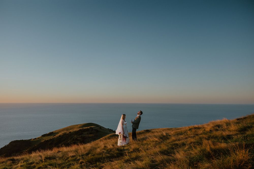 Elopement vow exchange on a scenic cliff overlooking the ocean, on Pepin Island. Howdy Pictures - film wedding photographers in New Zealand