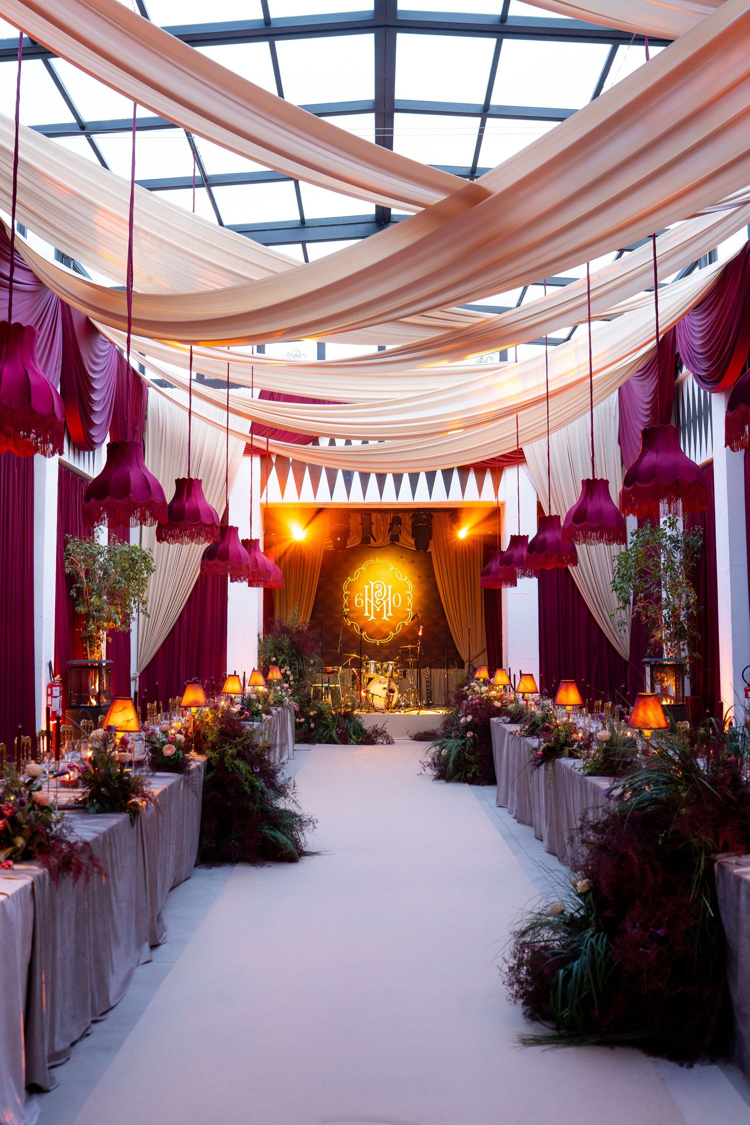 Elegant wedding venue with draped fabric ceiling, purple curtains and ambient lighting creating a romantic atmosphere.