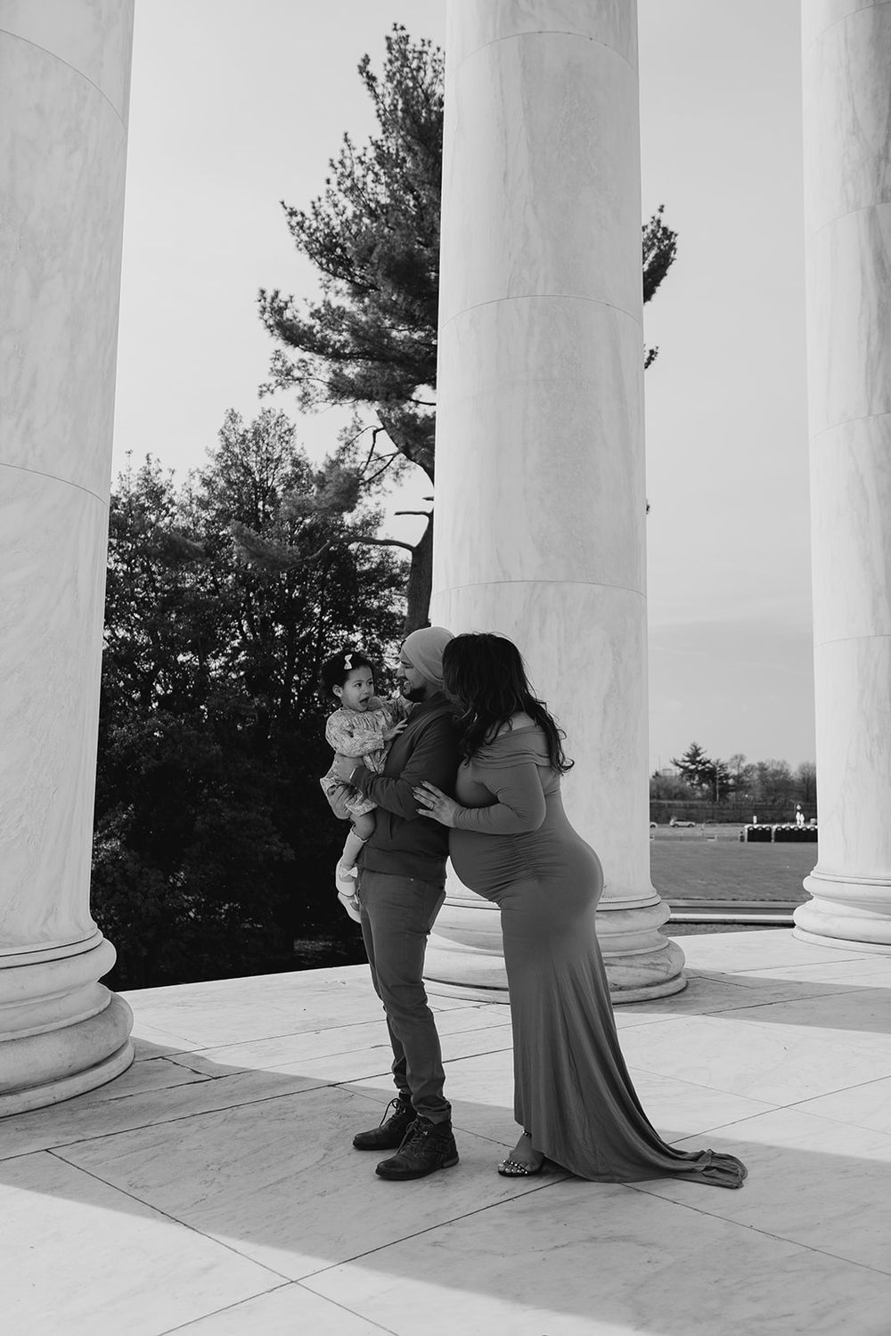 A romantic proposal sequence captured in black and white between columns at a classical building entrance.