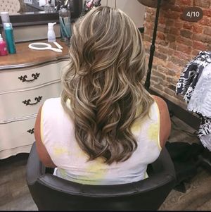 Hair styling process showing the back view of wavy brown hair being styled in a salon setting.
