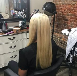 Hair styling process showing platinum blonde hair extensions being applied in a professional salon setting.