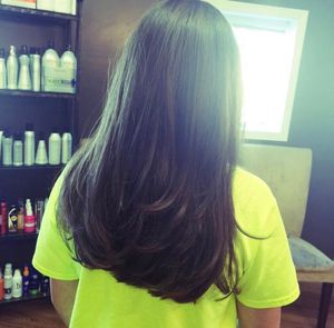 Back view progression of dark hair in a salon setting with natural lighting through windows.