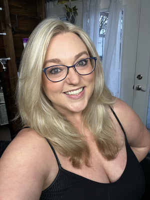 A person with blonde hair and glasses takes a series of selfies in a black tank top near a white door.
