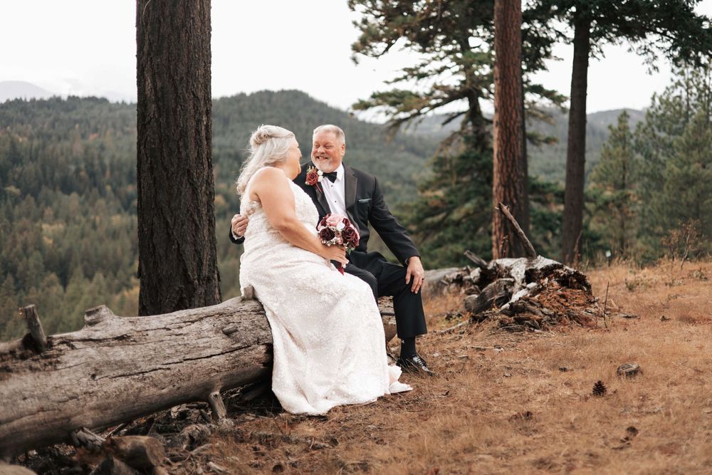 Suncadia, WA wedding couple, man and woman sitting on a log looking at each other with Mountain View in background.