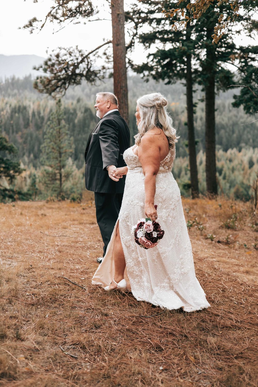 Woman in wedding dress holding a bouquet and holding hands with husband walking in a forest. Suncadia wedding photography.