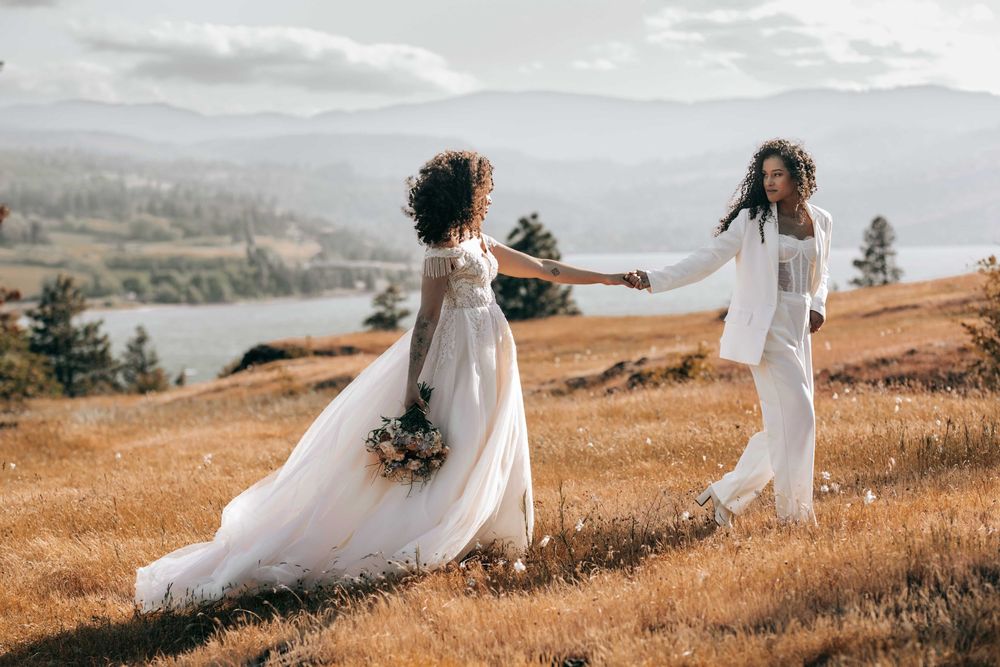 Ellensburg, WA wedding couple walking on tall brown grassy scene with Columbia River in the background.
