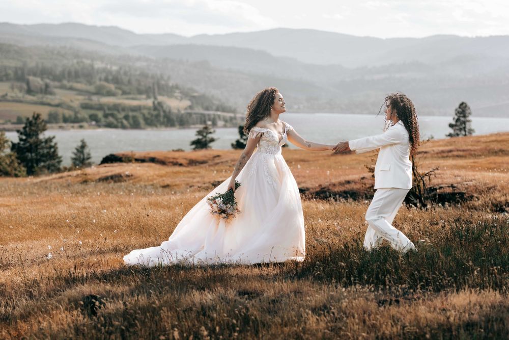 Ellensburg, WA wedding couple walking on tall brown grassy scene with Columbia River in the background.