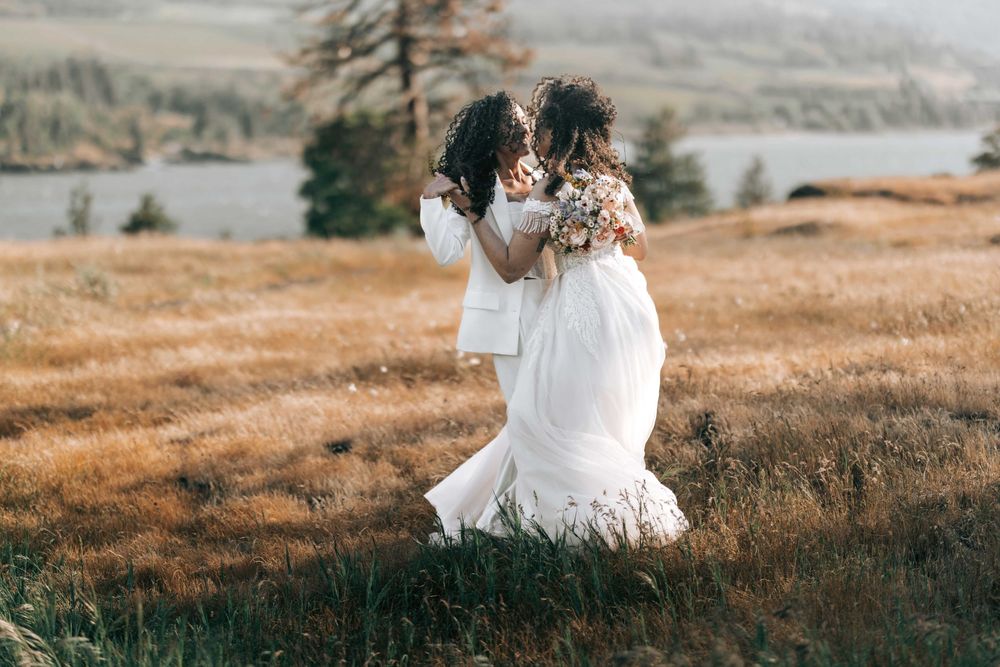 Ellensburg, WA wedding couple walking on tall brown grassy scene with Columbia River in the background.