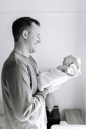 Black and white photo series showing a person in profile holding and looking at a small infant against a white background.