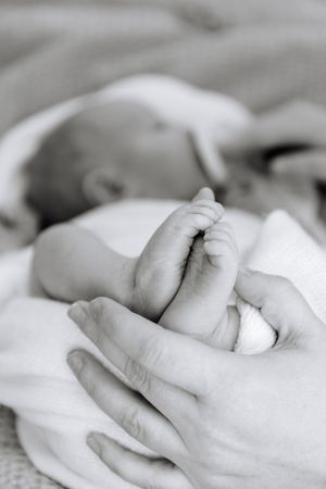 Black and white close-up images of gentle hands holding and caressing a newborn baby.