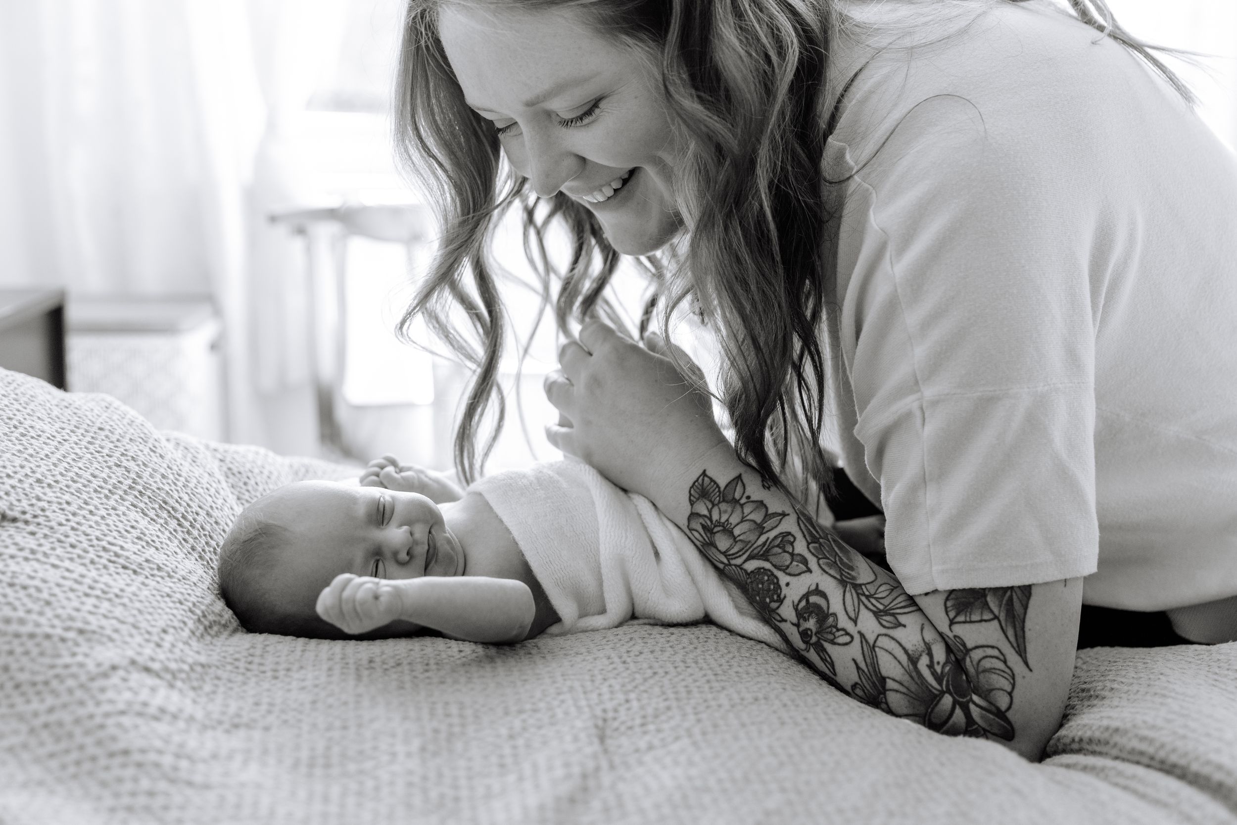 A series of intimate black and white photos showing tender moments between parent and baby on a bed.