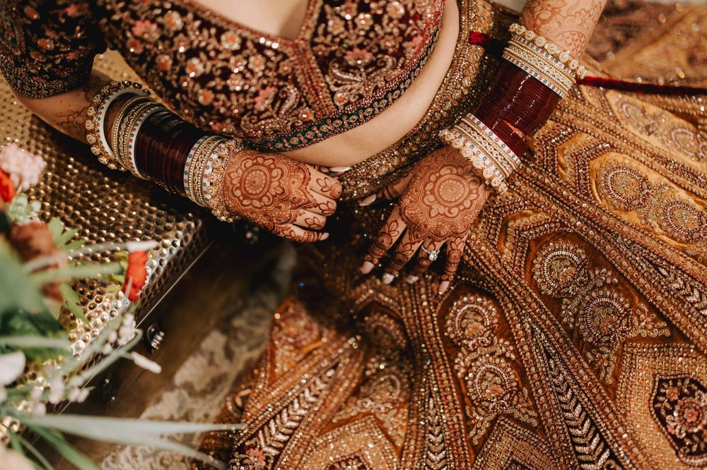Detailed view of elaborate gold embroidery patterns on brown fabric with traditional Indian design elements.