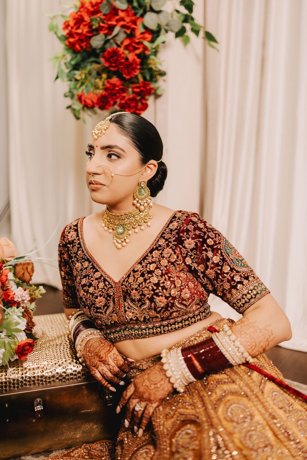 Detailed view of maroon velvet bridal lehenga with intricate gold embroidery and jewelry accents.