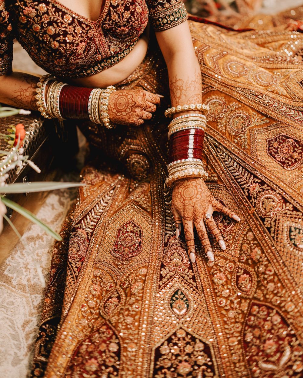 Intricate gold embroidery details on a deep red traditional Indian wedding lehenga.