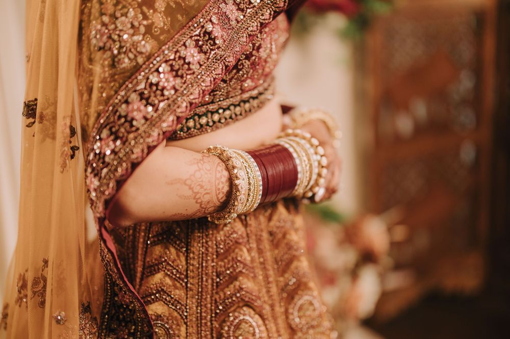 Close-up details of ornate golden embroidery work and jewelry on traditional Indian bridal attire.