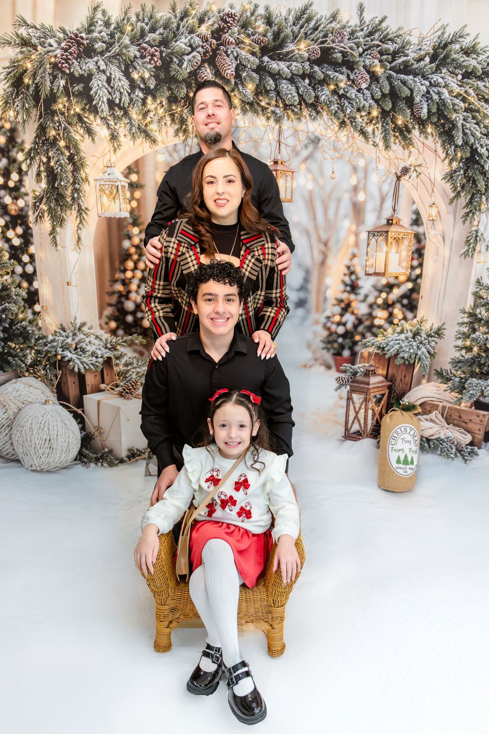 Family photo session in a cozy winter wonderland setting with festive decorations and evergreen garlands.