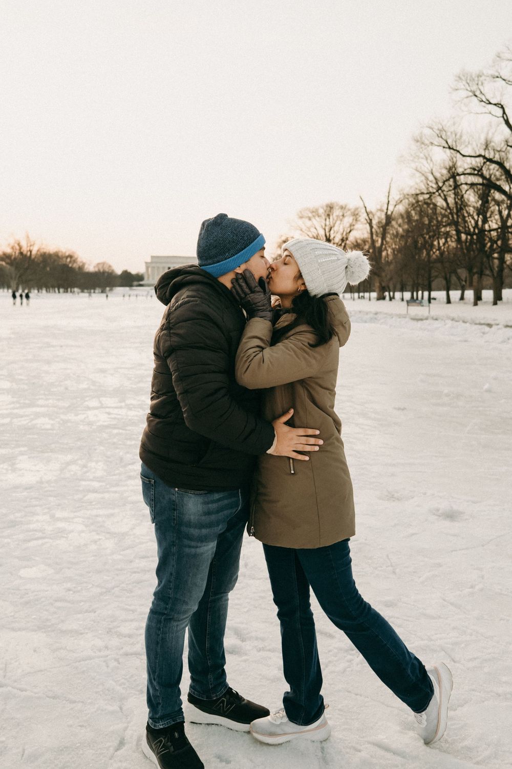 Two people dance and embrace on a snow-covered field during winter.