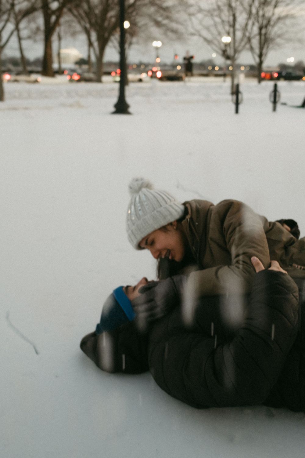 A couple playfully falls into the snow during a romantic winter photoshoot.