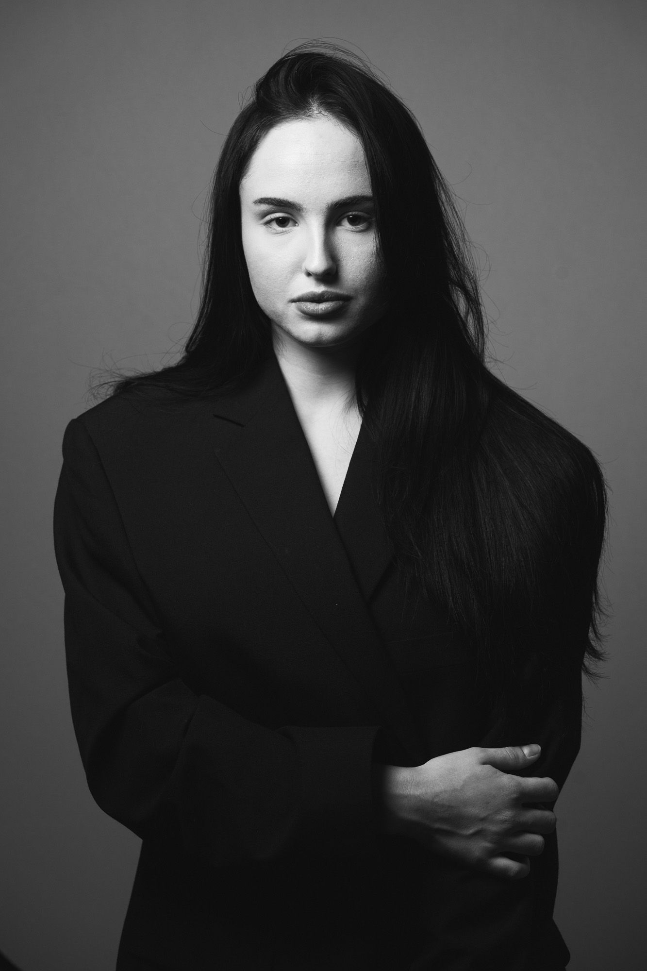 black and white portrait of a young woman in a black blazer on a grey background taken in a studio in King's Lynn by N-lite Photography