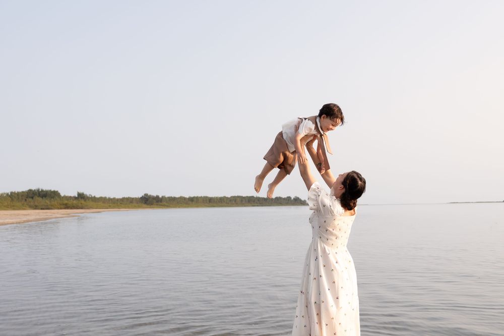 A mother and son share fun moments on a sandy beach during sunset.