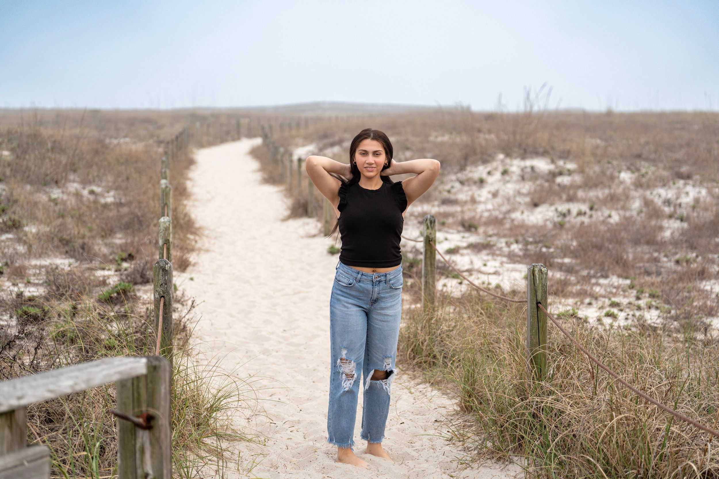 Sandy pathway winding through coastal dunes and beach grass.