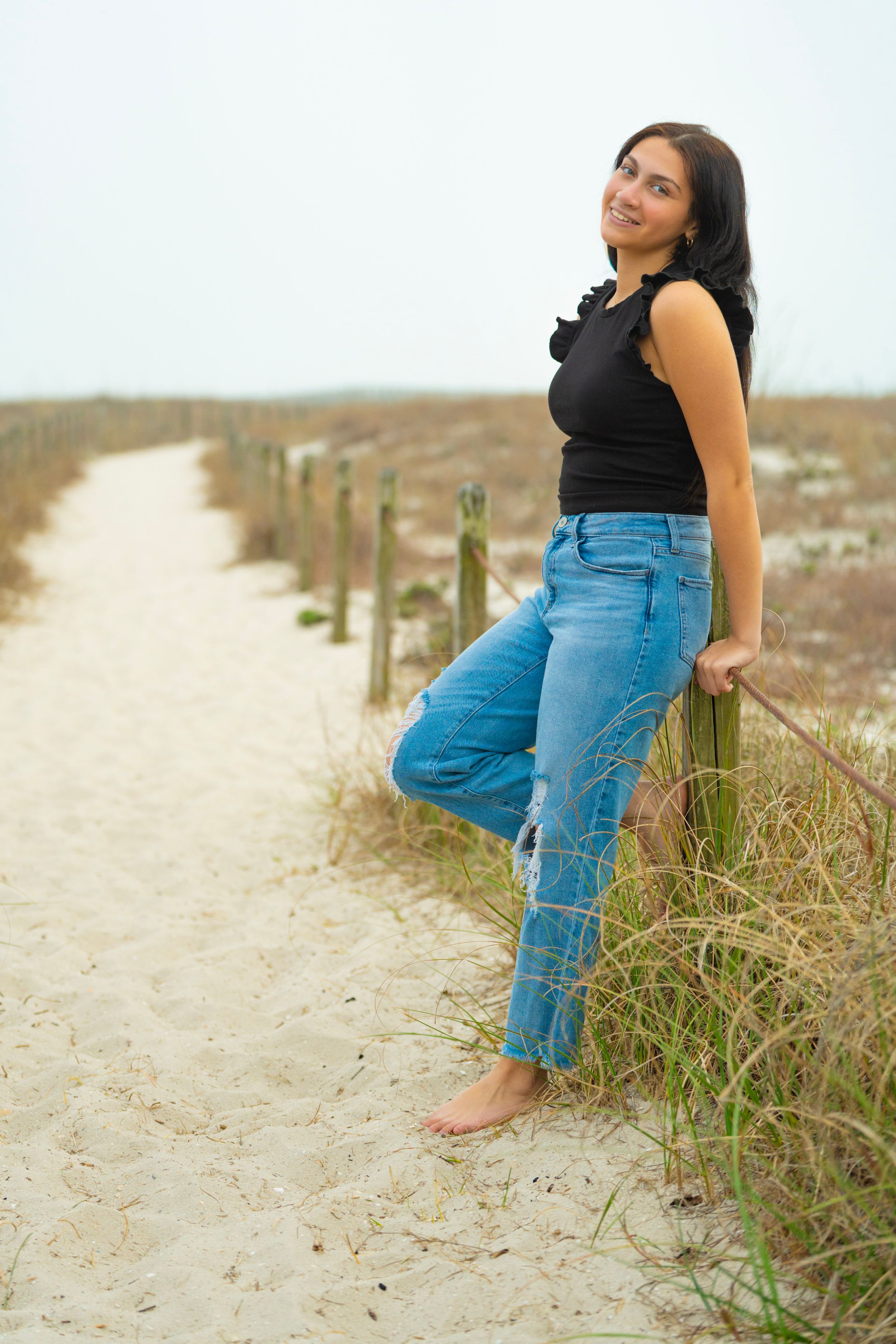 Sandy beach path with coastal vegetation and dunes along the shoreline.