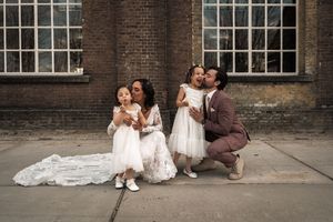 A couple in wedding attire sits together on brick steps outside a historic building.