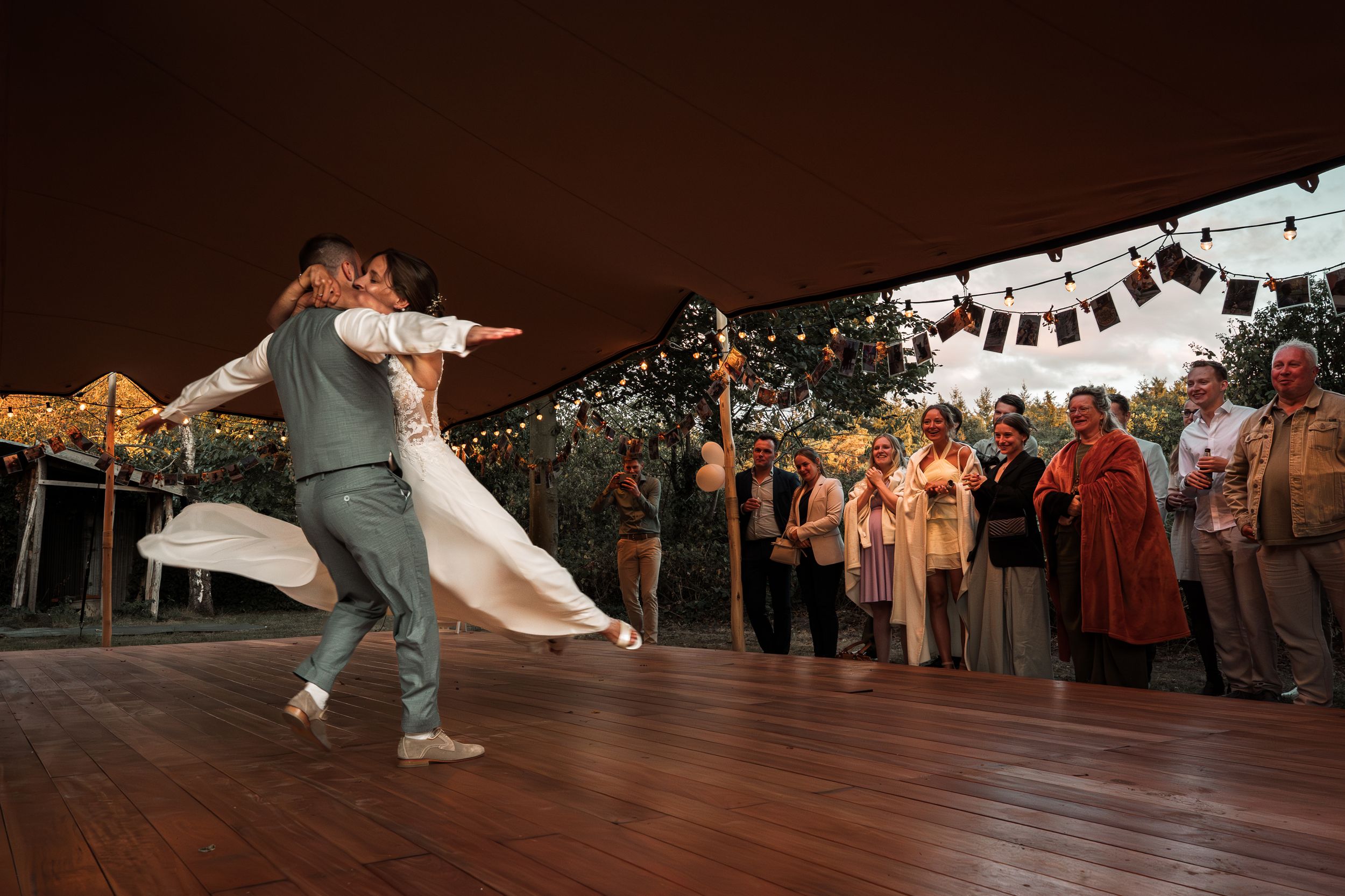 Dancers perform energetic swing dance moves on a wooden dance floor during a social dance event.