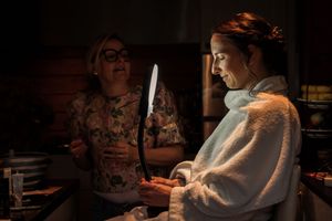 Two people in a dimly lit kitchen preparing food together, with warm lighting creating a cozy atmosphere.