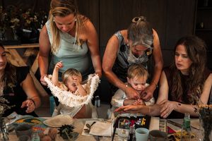 Two children and several adults gather around a table during what appears to be a celebration or party.