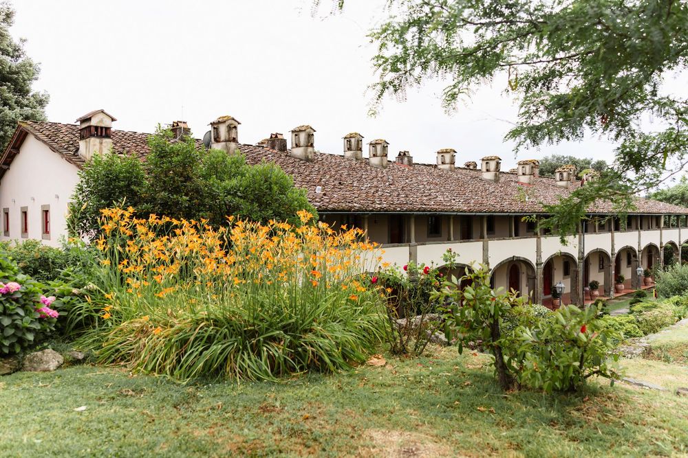 Garden path lined with vibrant yellow flowers and rustic stone buildings in an Italian countryside estate in Artimino, Tuscany