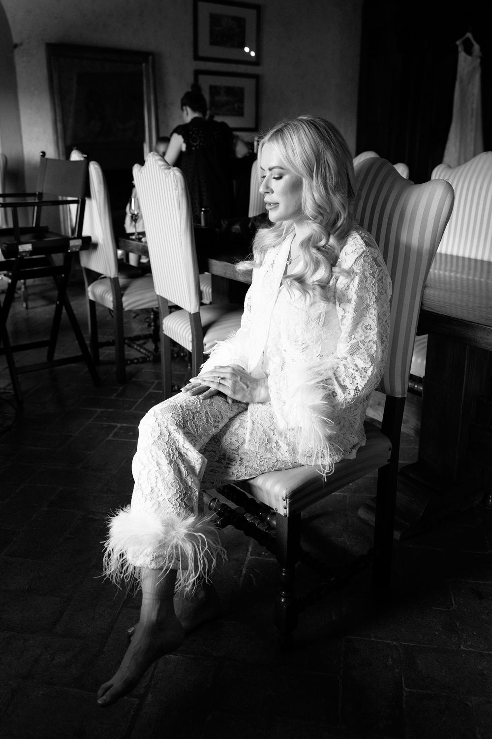 A figure in white lace sits peacefully in a striped chair during a quiet moment.