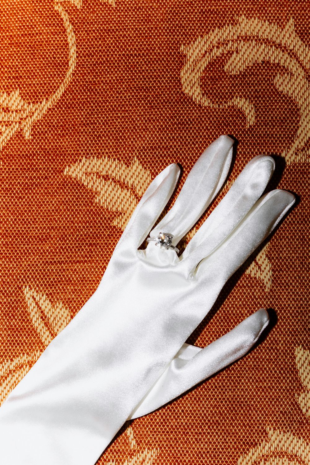 A sequence of white gloves arranged in a diagonal pattern against a reddish-orange textured background.