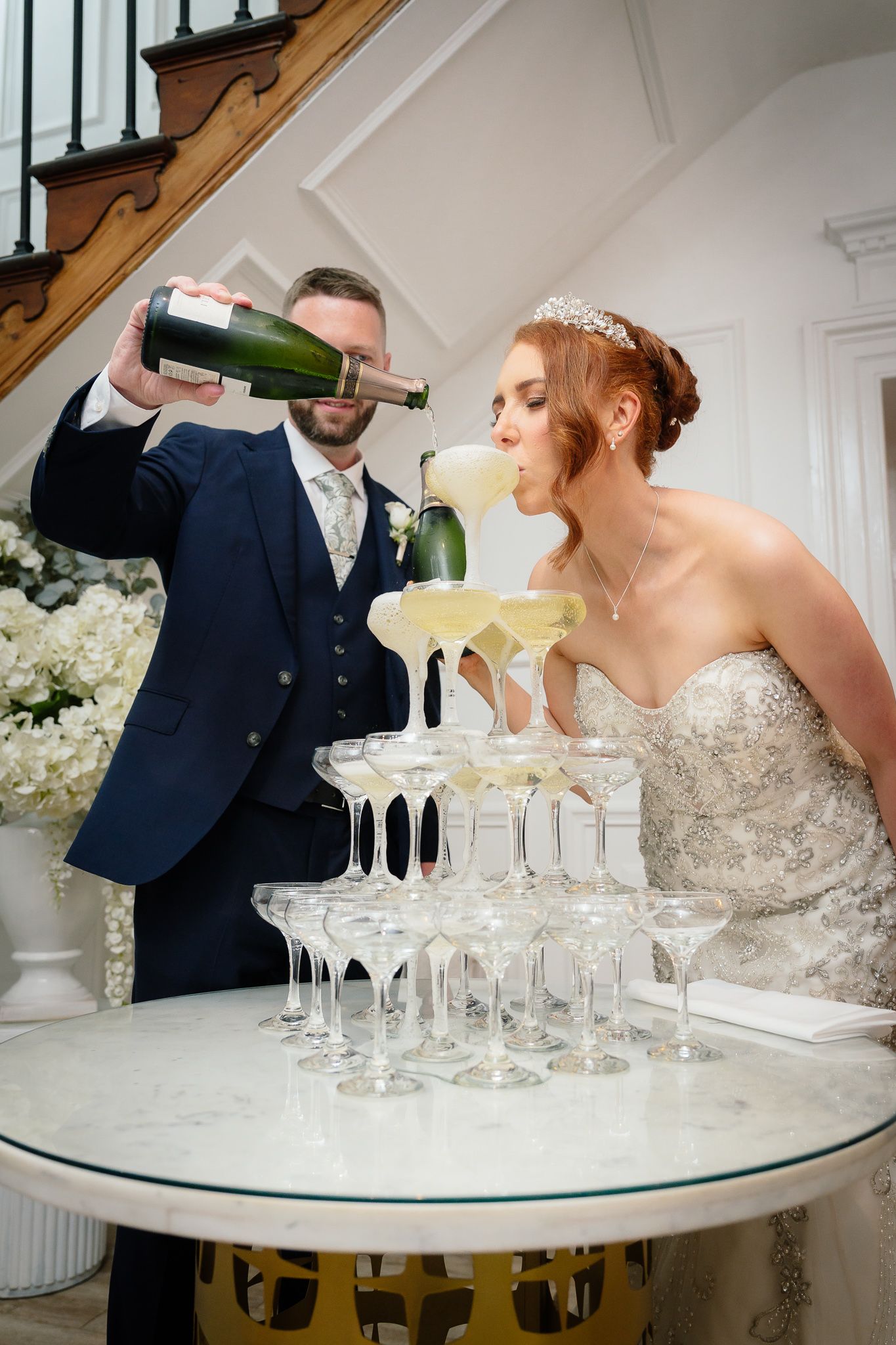 Champagne being poured into a tower of glasses at an elegant wedding reception. Woodhill Hall.