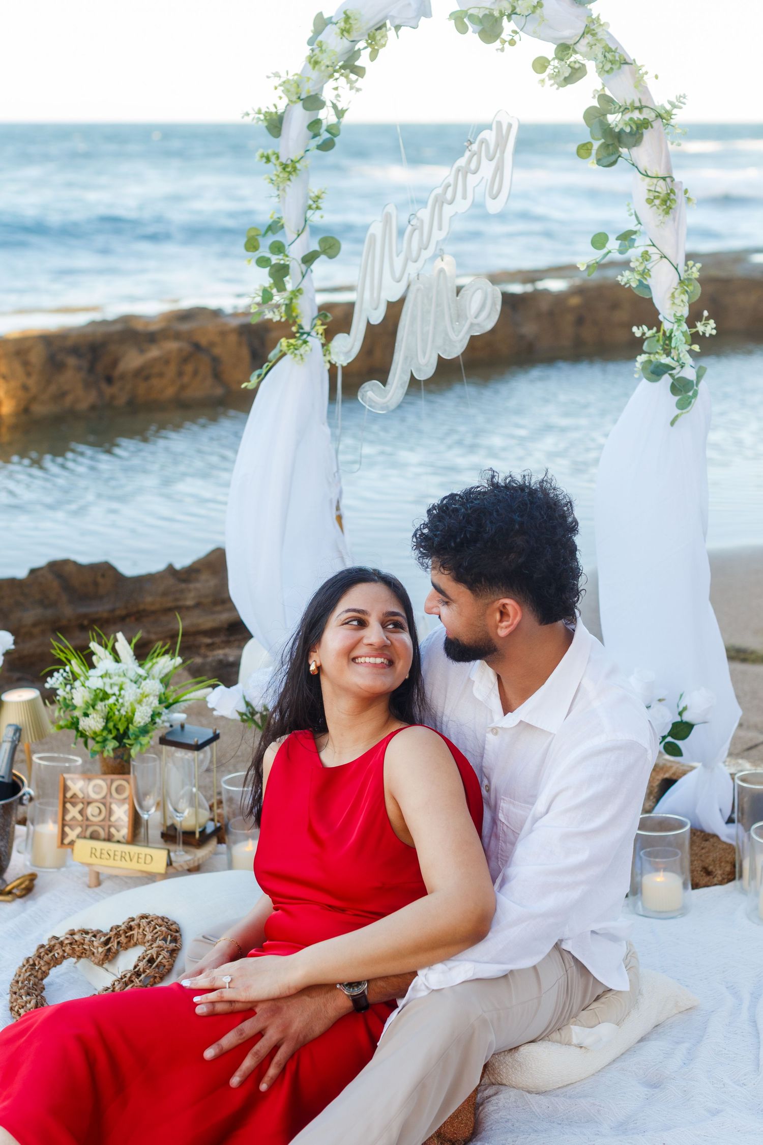 Couples portrait. Proposal and engagement session. Man and woman seated on the beach. Kikita Surf Beach, Dorado, Puerto Rico.