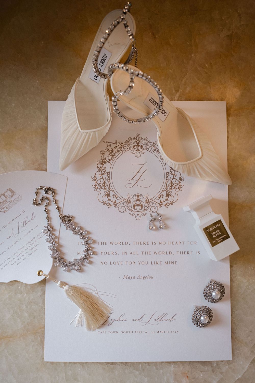 White wedding invitation suite with diamond jewelry, heels, and bridal accessories flatlay.