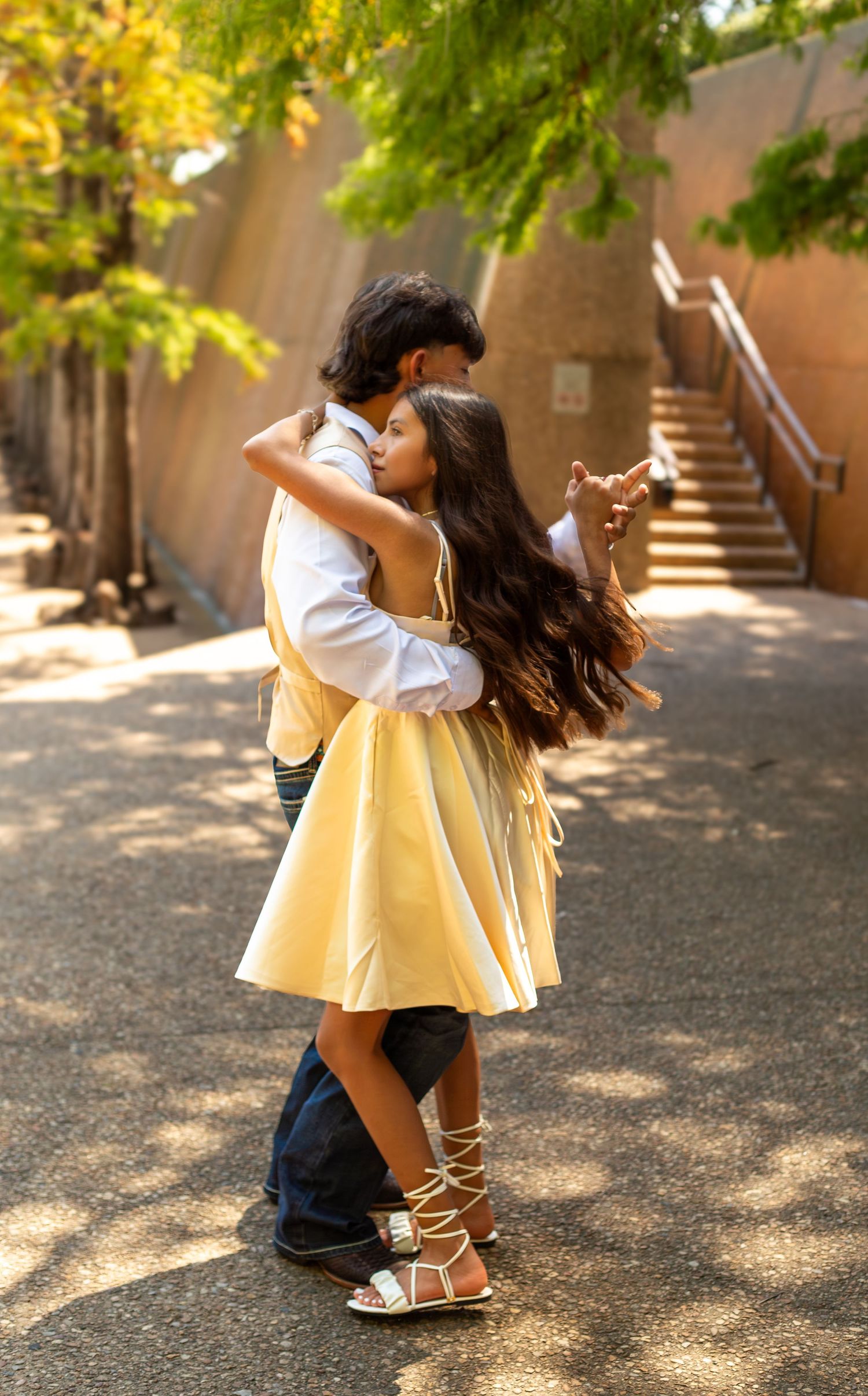 A couple embraces against a stone wall during a sunset photo session, creating a romantic and intimate moment.
