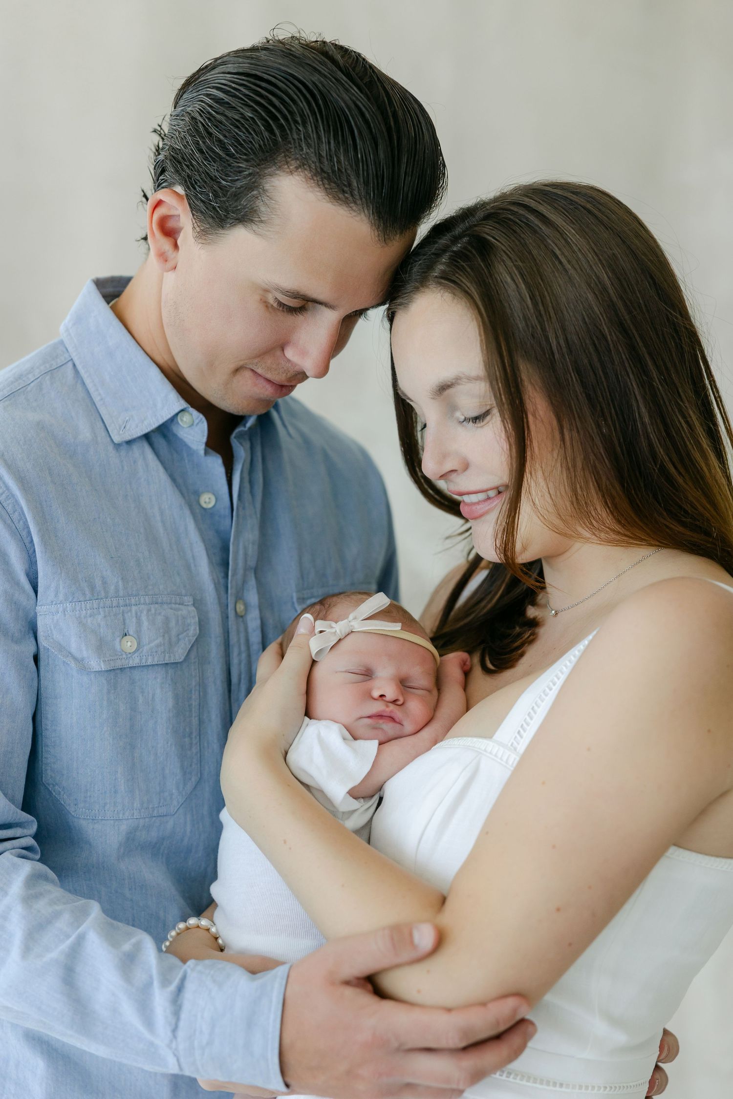 A tender series of photos showing parents cradling and bonding with their newborn baby in soft natural light. Connecticut Newborn Studio.