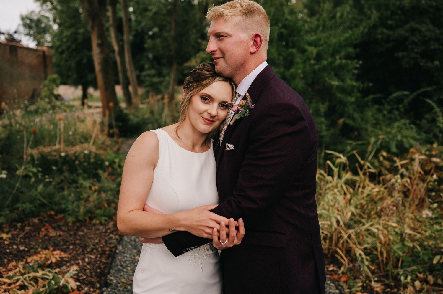 A couple shares a tender moment in an autumn walled garden setting.