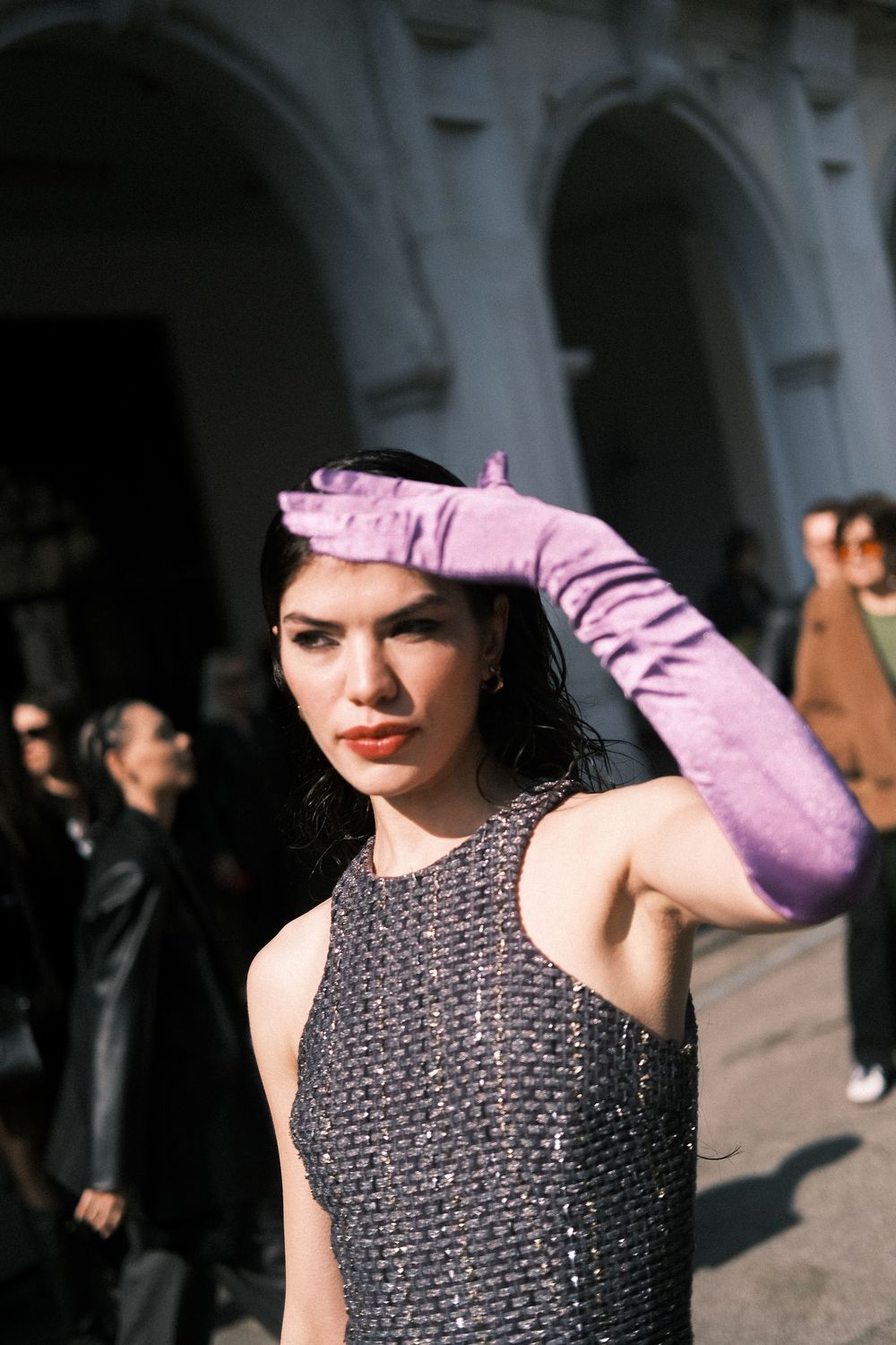 A model walks down a runway wearing a sparkly sleeveless dress and long pink gloves in a fashion show sequence.