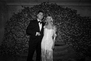 Formal wedding portrait in front of a lush floral wall backdrop.