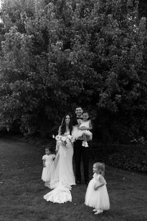 Wedding party gathering for formal portrait in garden setting.