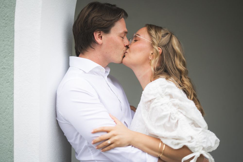 A couple shares an intimate moment while sitting beneath an elegant white archway.