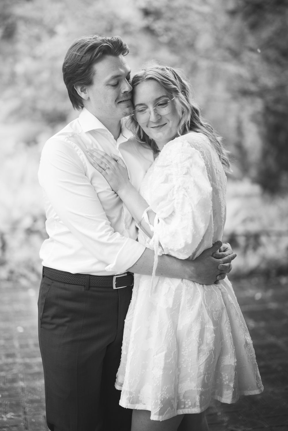 Black and white romantic photo series showing a couple embracing outdoors in a tender moment.
