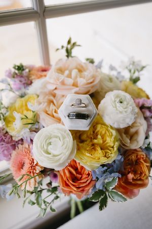 Delicate floral arrangements featuring peach, yellow and white roses displayed along a windowsill.