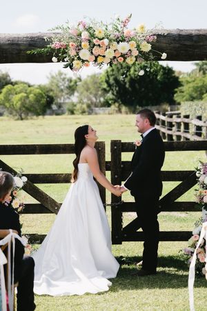 Wedding ceremony moments captured against a rustic wooden fence decorated with floral arrangements.
