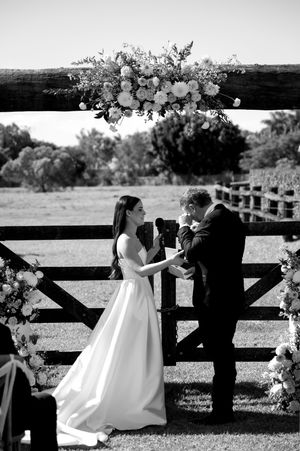 A romantic wedding sequence showing a couple by a rustic wooden fence with floral decorations.